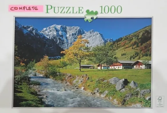 A photograph of a serene Alpine valley featuring a rushing stream, lush green meadows, rustic houses, and tall mountains.