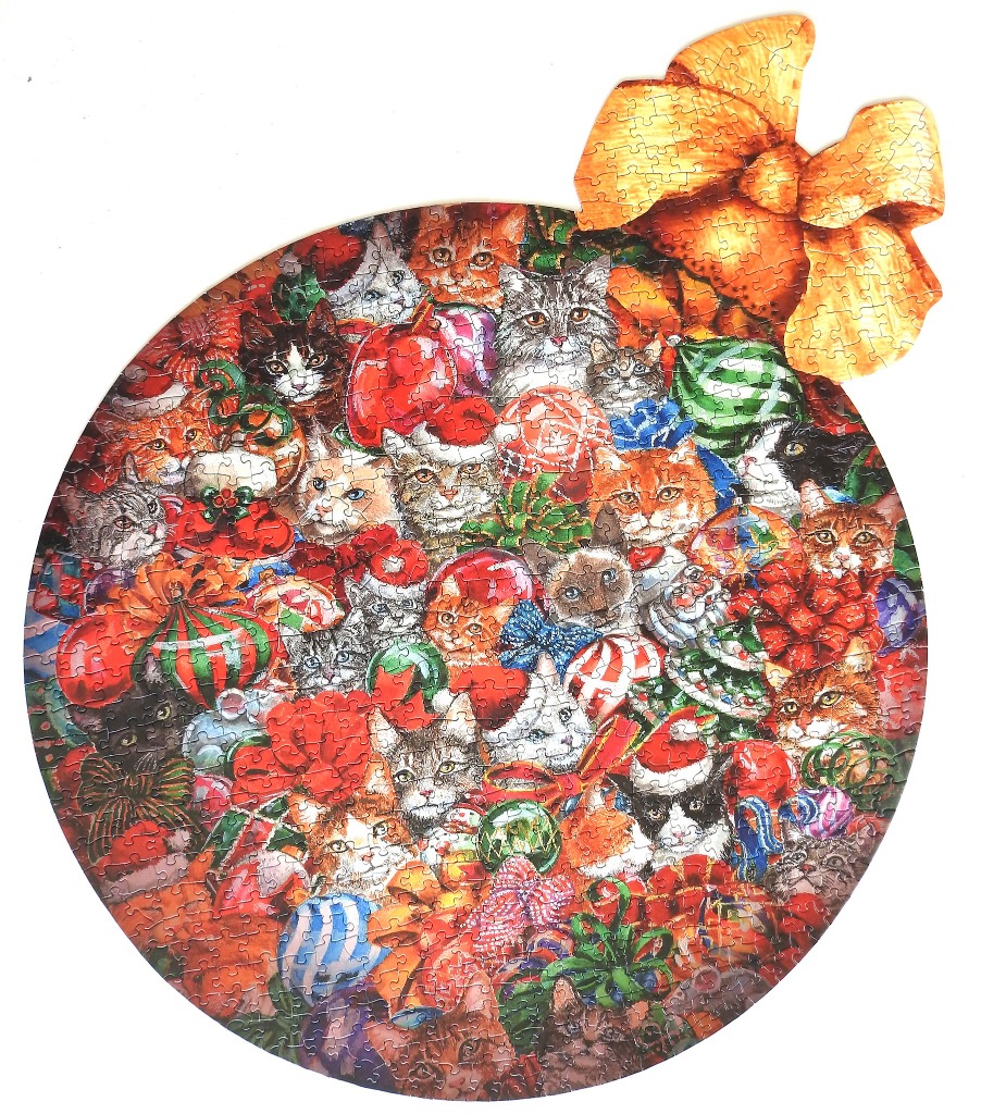 A round Christmas ornament illustration featuring many kittens nestled among holiday decorations and red bows.