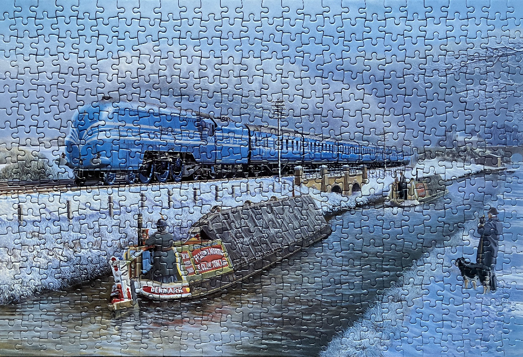 A blue steam locomotive traveling past a canal barge in a winter landscape.