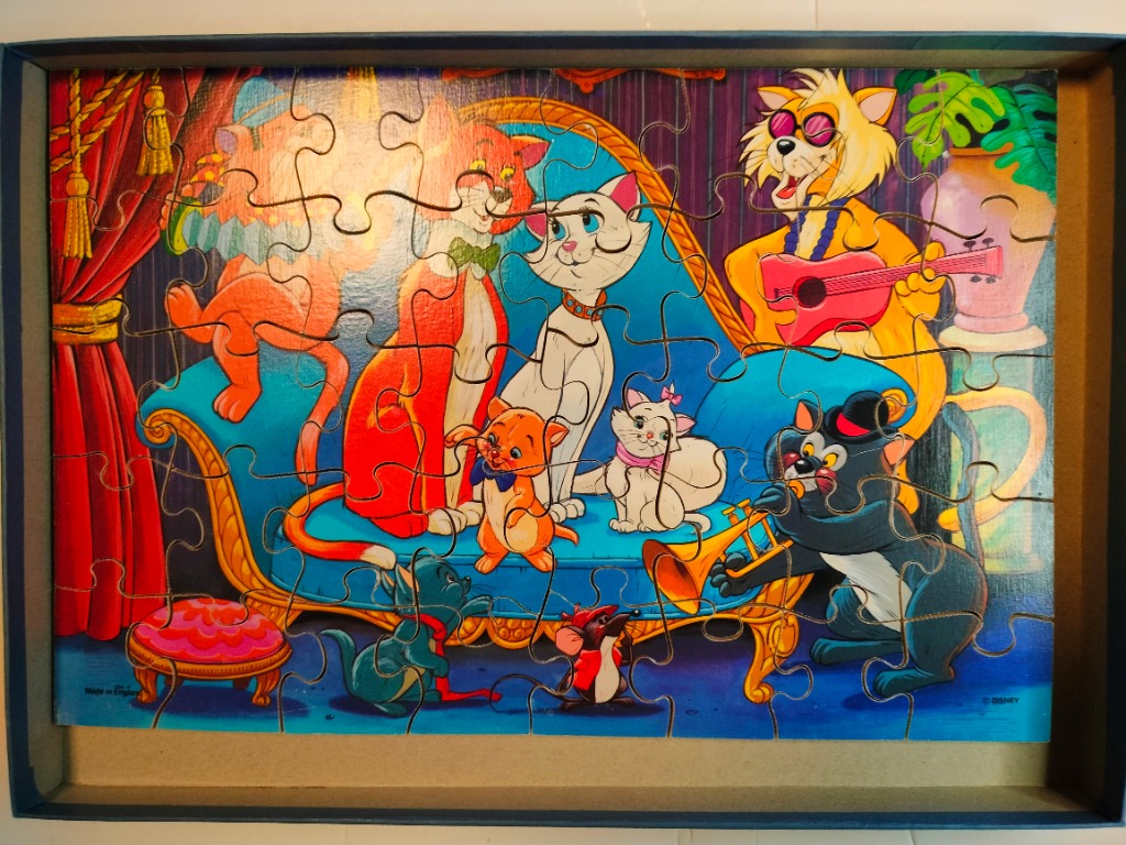 An illustration of jazz-playing cats from The Aristocats sitting on a blue velvet sofa.