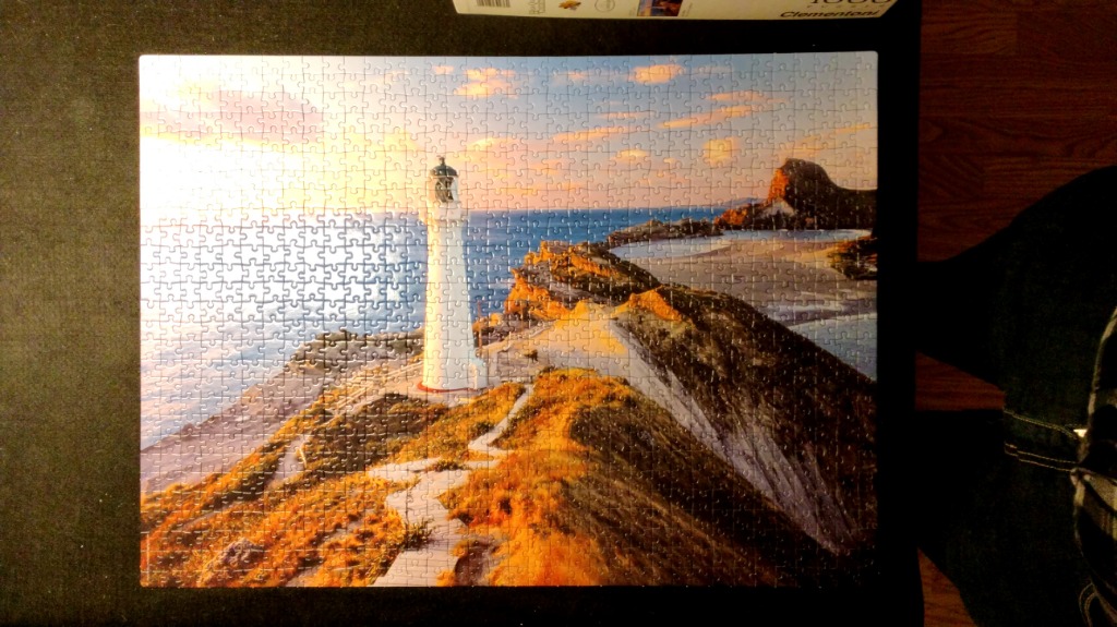 A lighthouse overlooking a coastal cliffside at sunset.