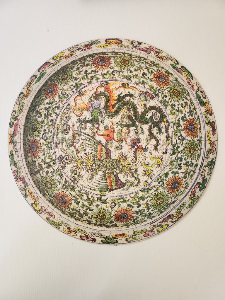 Round image of a green Chinese dragon and a phoenix bird surrounded by a floral vine border.