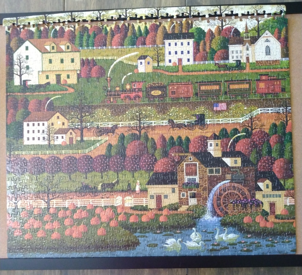 Folk art scene of a rural 19th-century village with a water mill, steam train, and pumpkin patch.