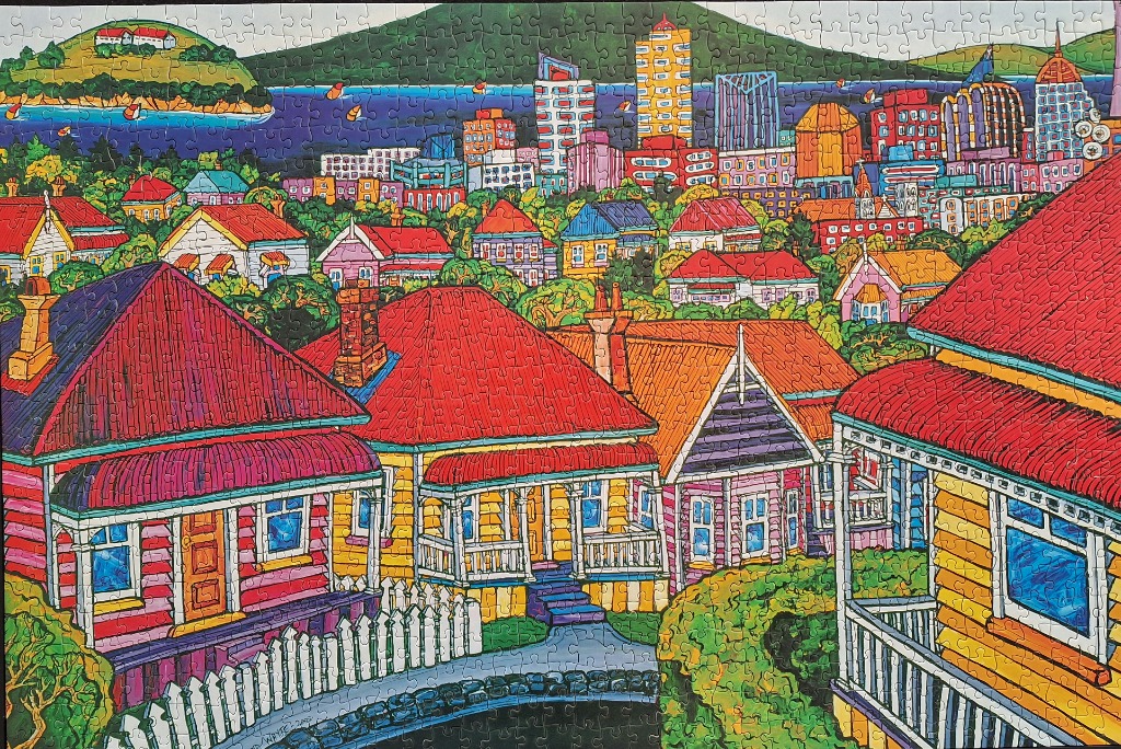 Colorful illustration of a hillside neighborhood overlooking a city and a distant bay with a green island.
