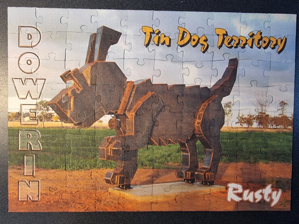 A metal sculpture of a dog named Rusty standing in a field with text overlays.