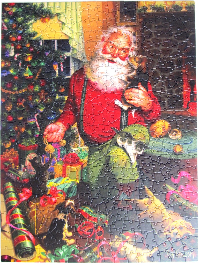 Santa Claus kneeling by a Christmas tree, holding a kitten and surrounded by presents