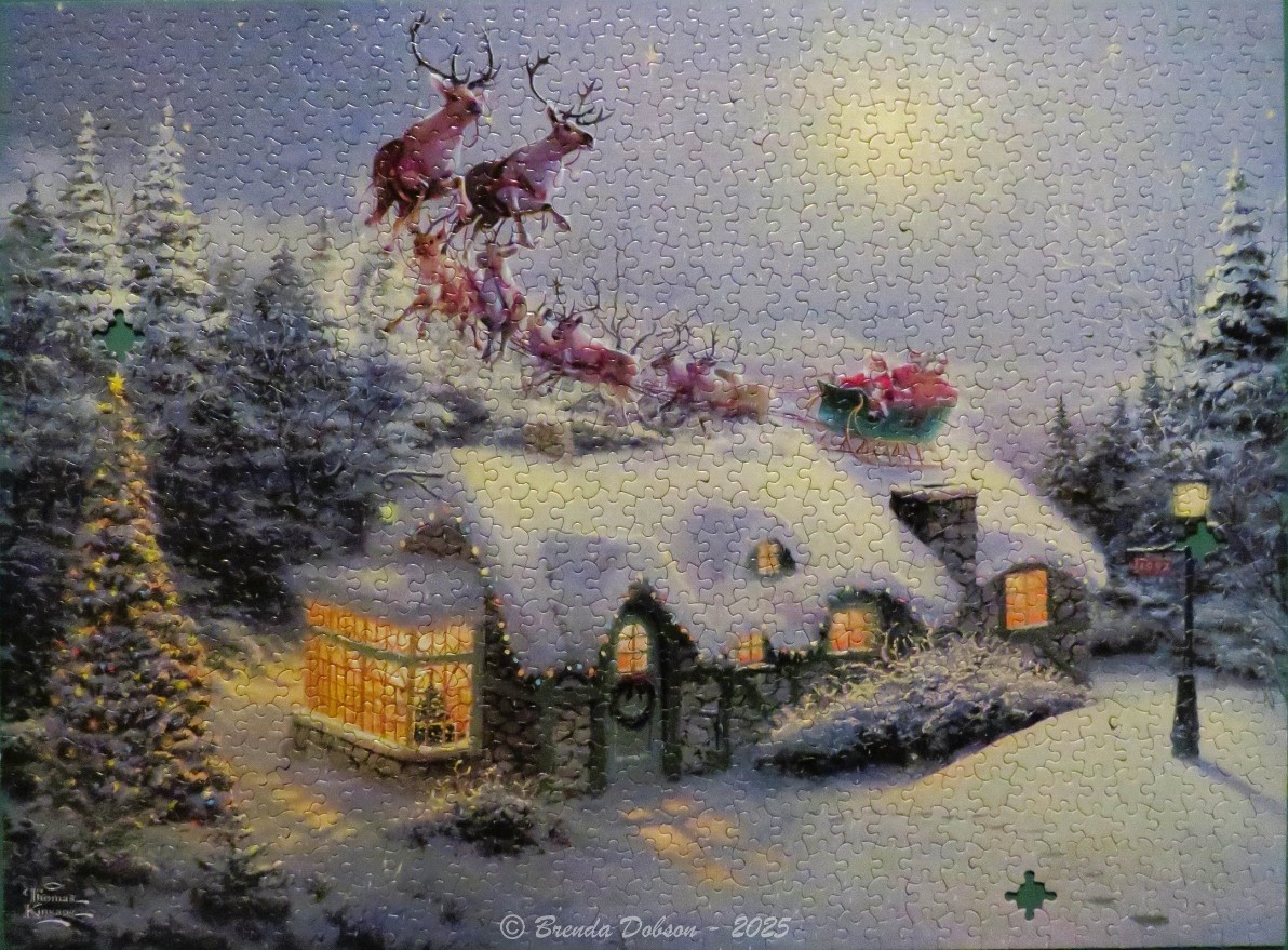Santa Claus and his reindeer flying over a snow-covered cottage at night