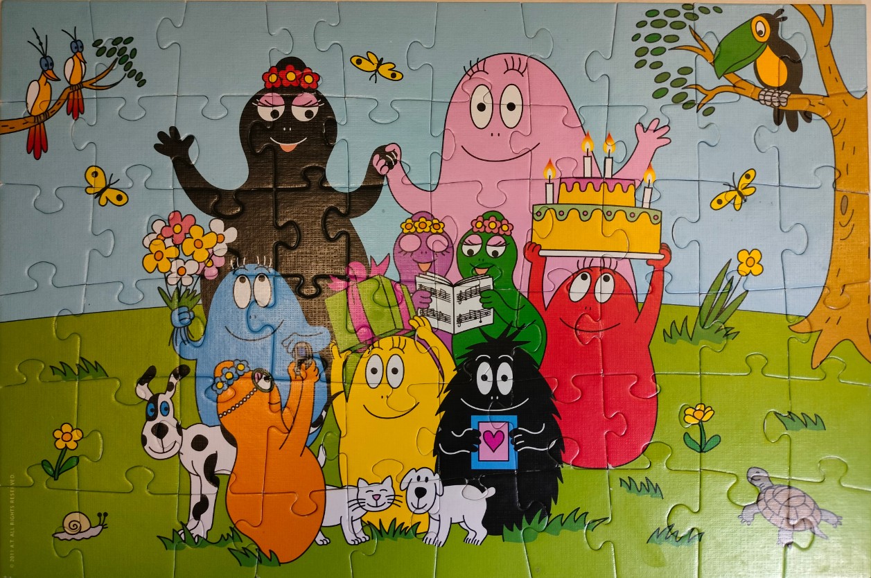 Cartoon scene featuring the Barbapapa family celebrating with a birthday cake in a grassy meadow.