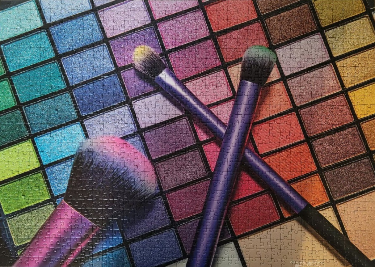 A close-up view of a vibrant eyeshadow palette with two makeup brushes laid across it.