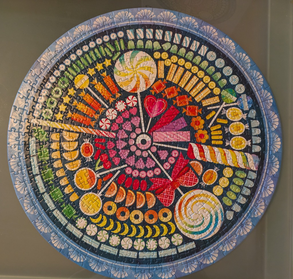 A circular arrangement of colorful assorted candies and sweets on a dark blue background.