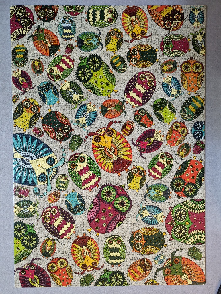 A collection of whimsical, patterned owls in varied sizes and vibrant colours scattered across a light grey background.