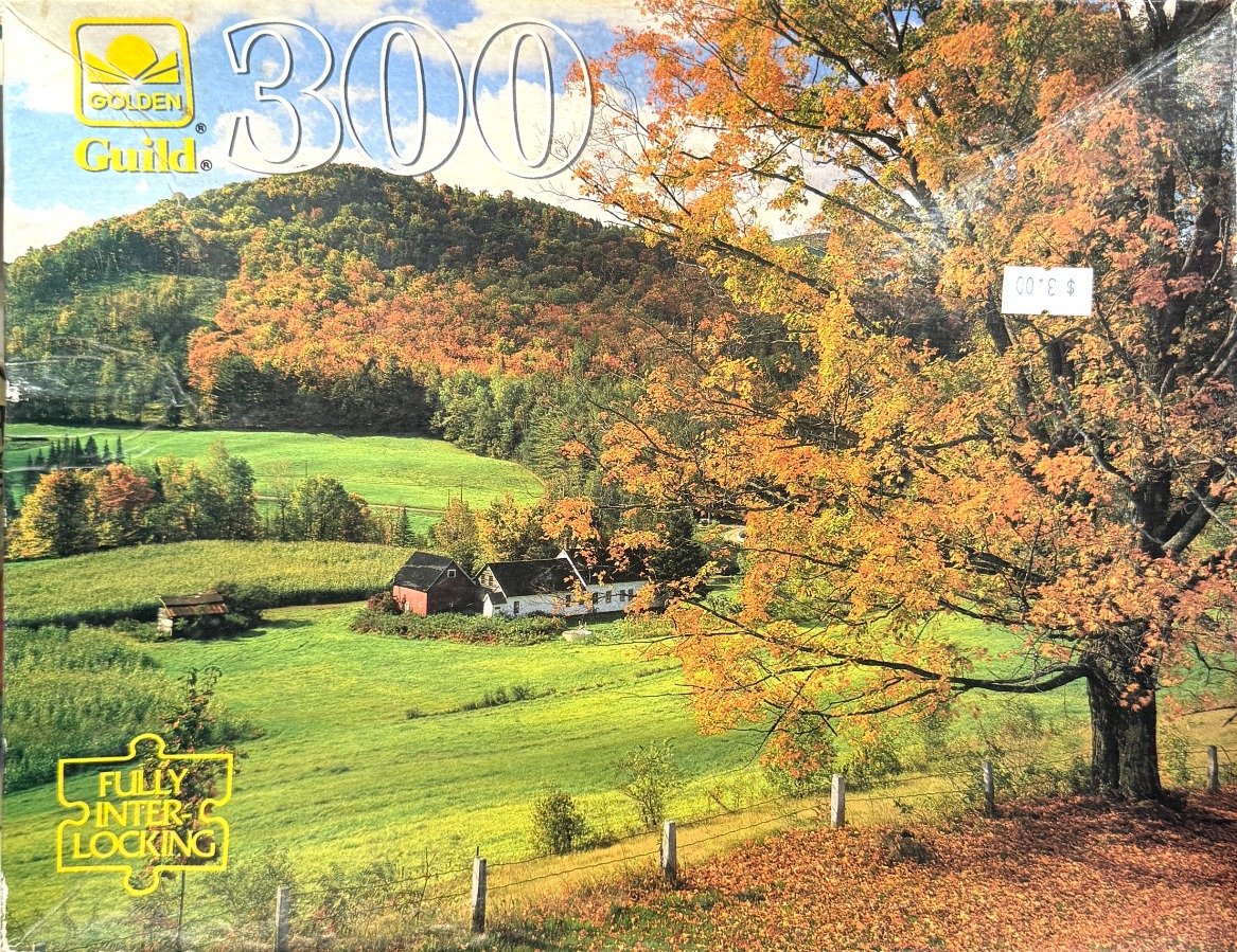 A peaceful autumn landscape featuring a white farmhouse in a green valley beneath rolling, tree-covered hills.