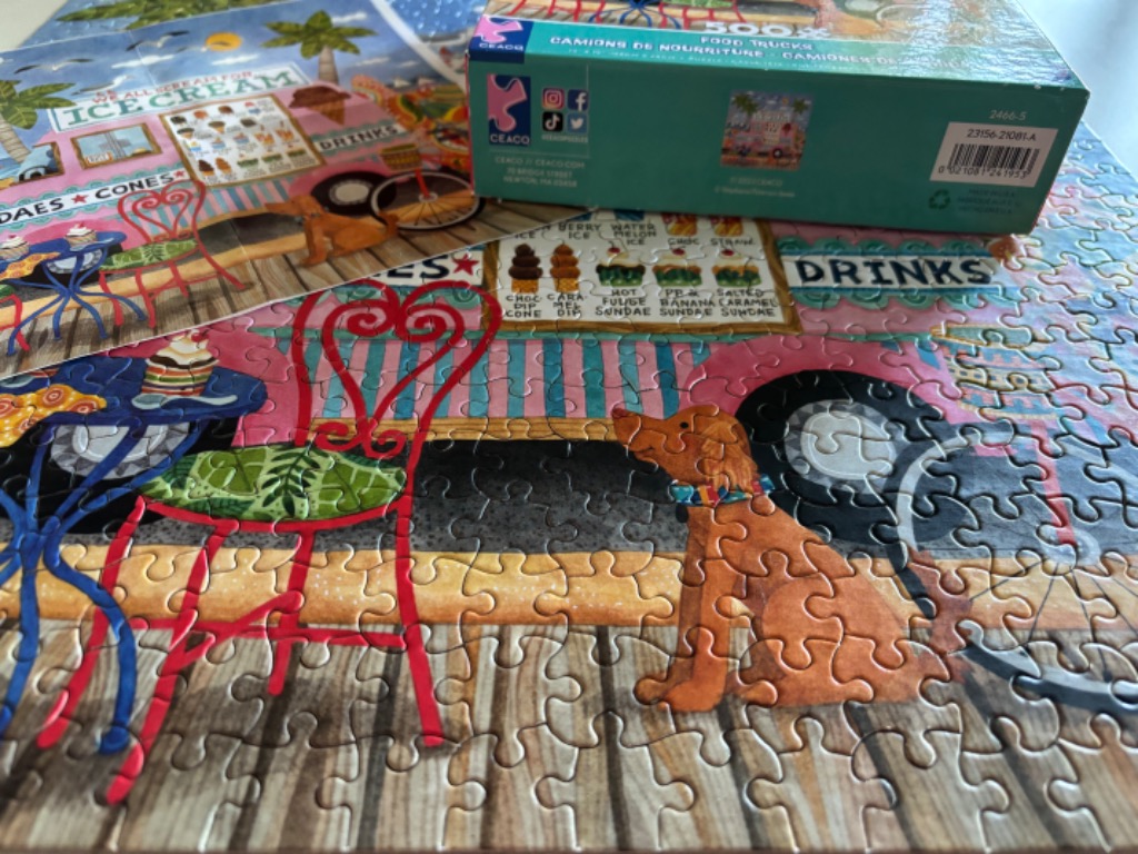 Brown dog at a vibrant ice cream truck with colorful chairs and tables.