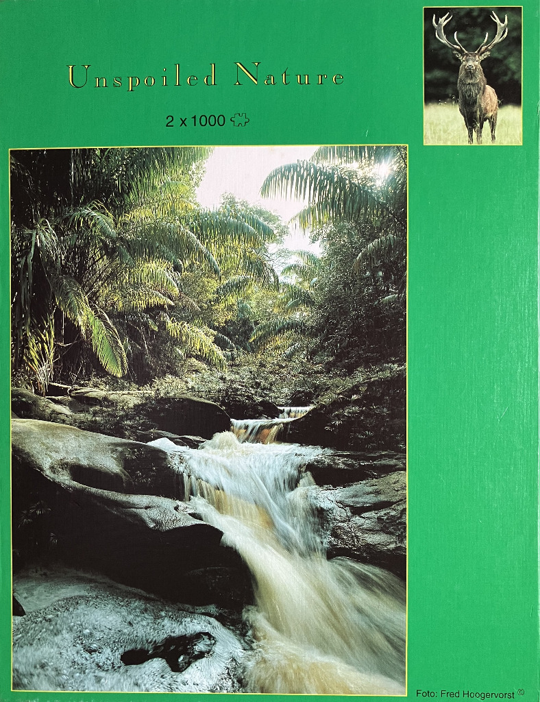 A photograph of a tropical stream cascading over dark rocks through lush, green palm foliage.