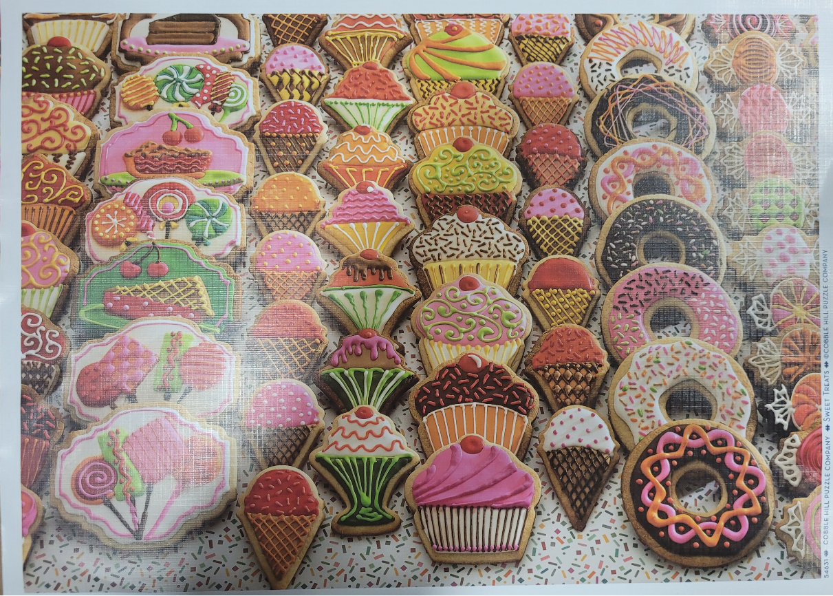 A dense grid of colorful, decorated cookies shaped like cupcakes, ice cream cones, and donuts.