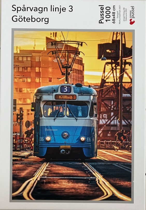 A blue vintage tram traveling on tracks in Gothenburg during a golden sunset.