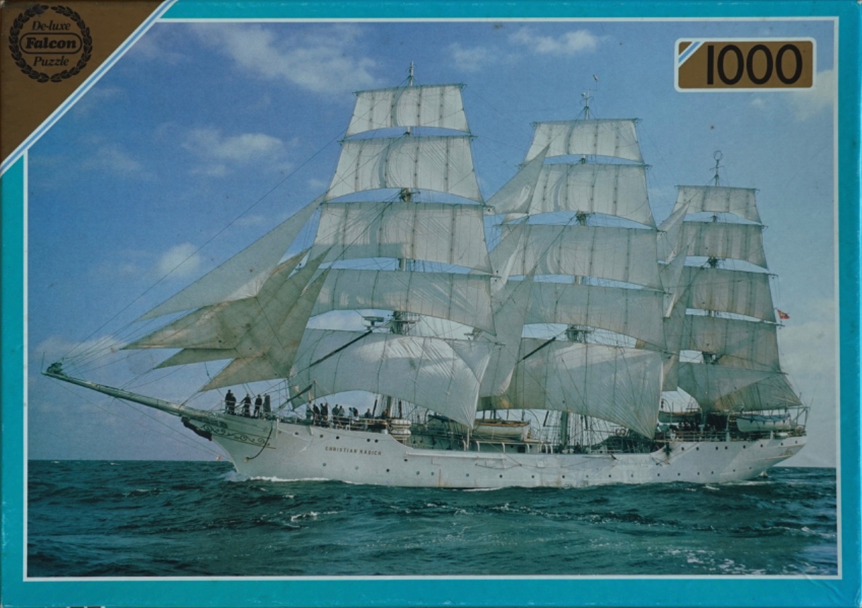 A three-masted tall ship, the Christian Radich, sailing on a blue sea under a bright, partly cloudy sky.