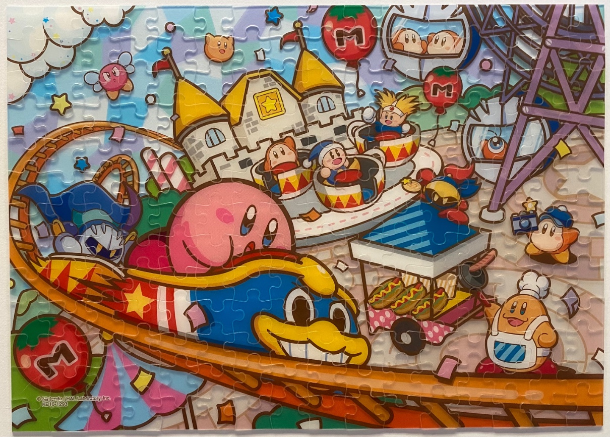 Colorful cartoon amusement park scene featuring Kirby characters on rides and at food stalls.