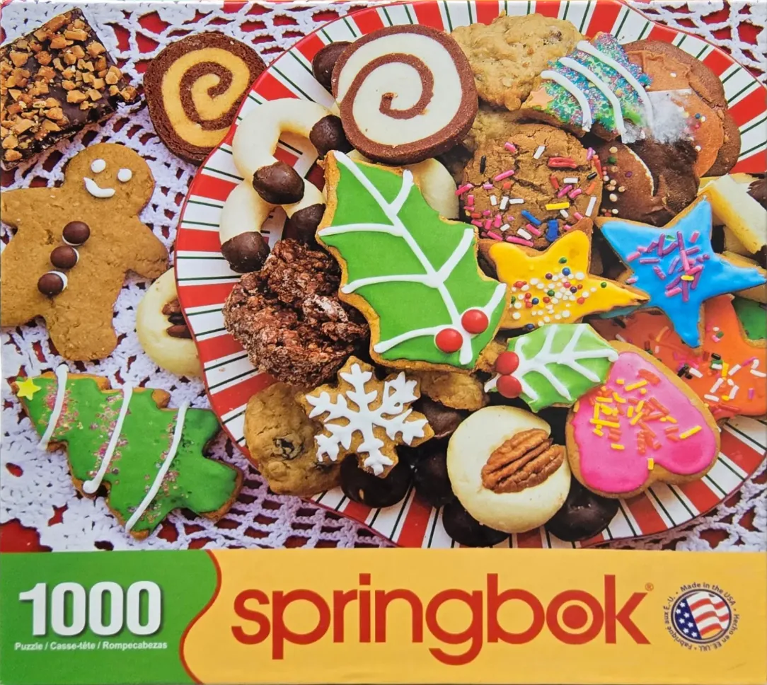 A top-down view of a colorful assortment of Christmas cookies piled on a striped festive plate.