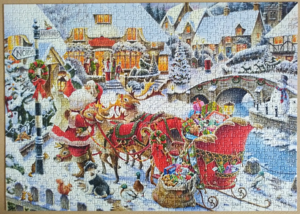 Santa Claus and his reindeer pulling a sleigh through a festive, snow-covered village at twilight.