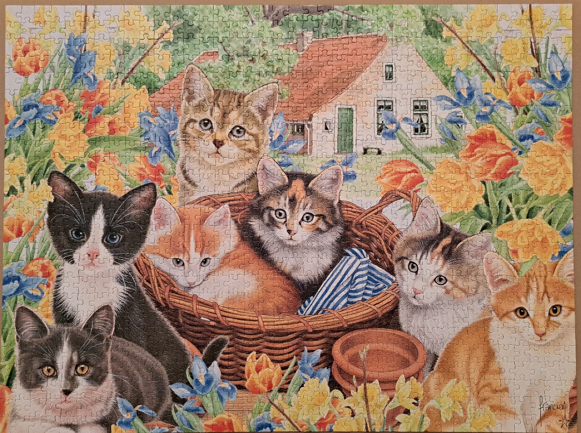 Six kittens gathered in and around a wicker basket in a vibrant spring garden.