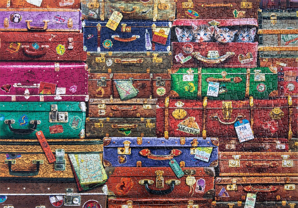A wall of vintage travel suitcases stacked on top of each other, covered in stickers and luggage tags.