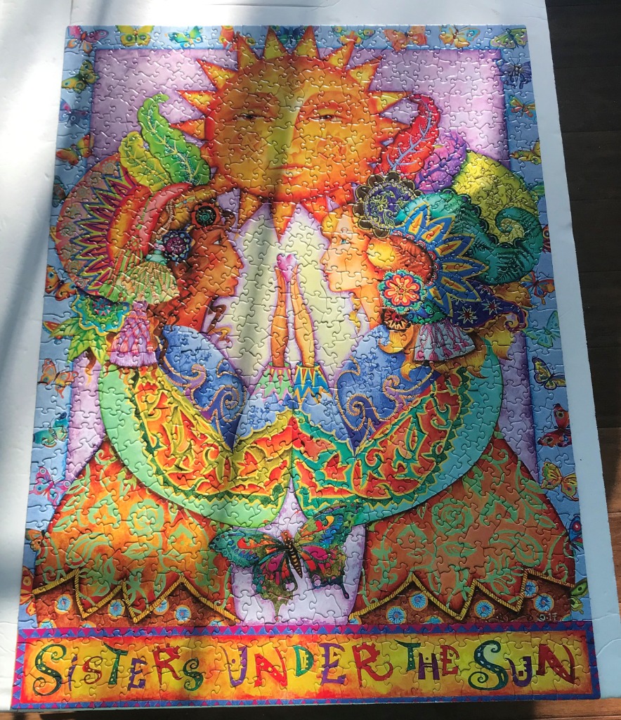 Two stylized women facing each other beneath a radiant sun, surrounded by butterflies in a vibrant folk art style.