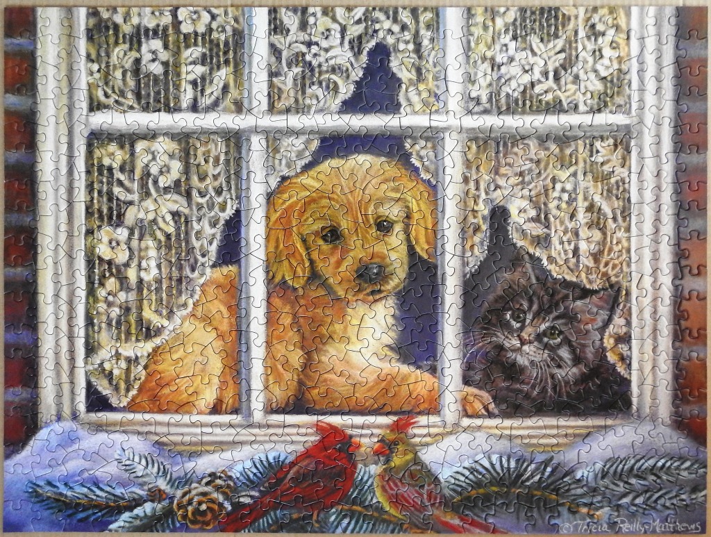 Golden retriever puppy and a fluffy black kitten looking through a window with winter birds on the sill.