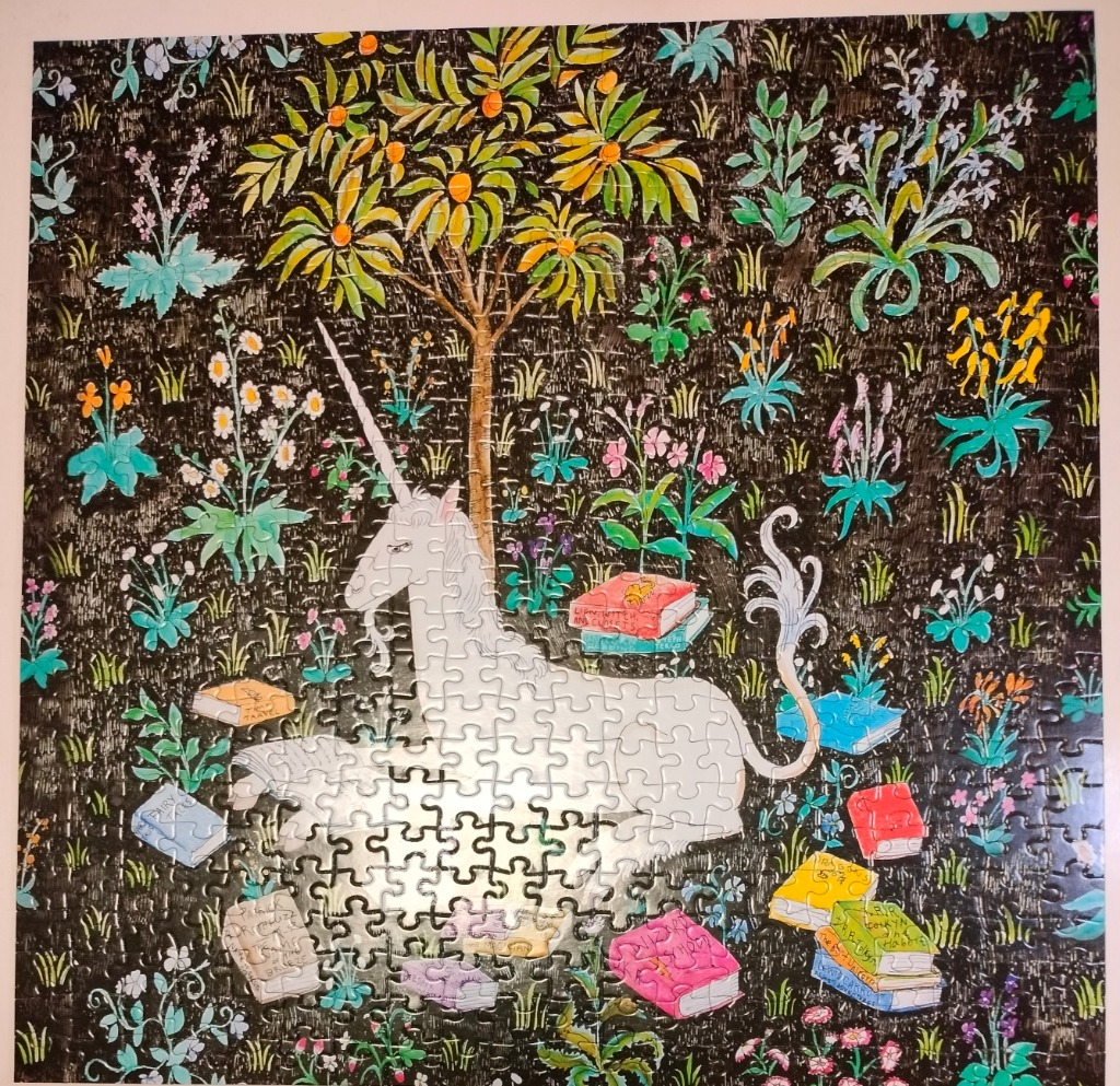 A whimsical illustration of a white unicorn sitting under an orange tree surrounded by various books on a dark background.