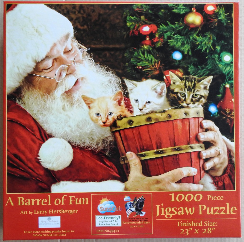 Santa Claus holding a wooden barrel filled with three small kittens in front of a Christmas tree.