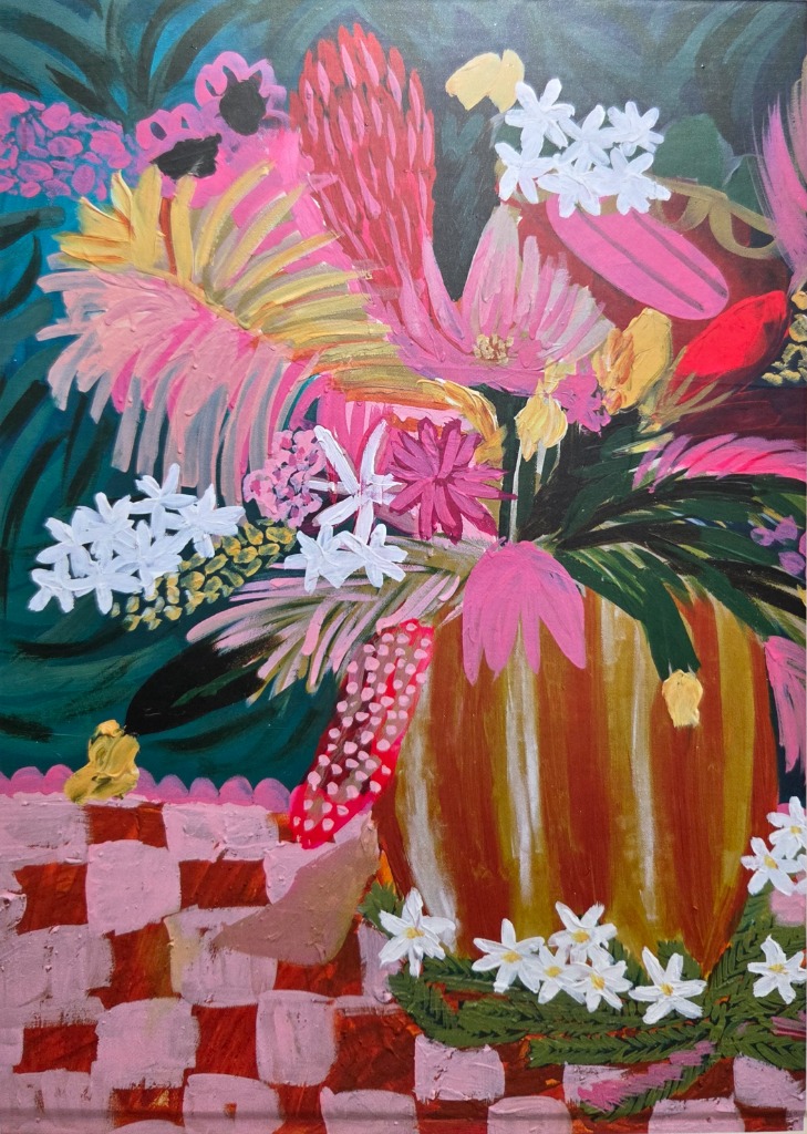 A vibrant, painterly arrangement of pink, yellow, and white flowers in a golden vase on a pink and red checkered surface.