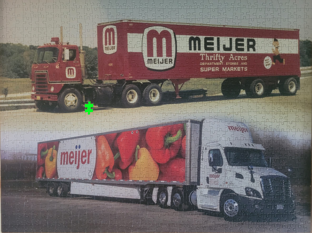 Two semi-trucks branded with the Meijer logo, one vintage red and one modern white with a pepper design.