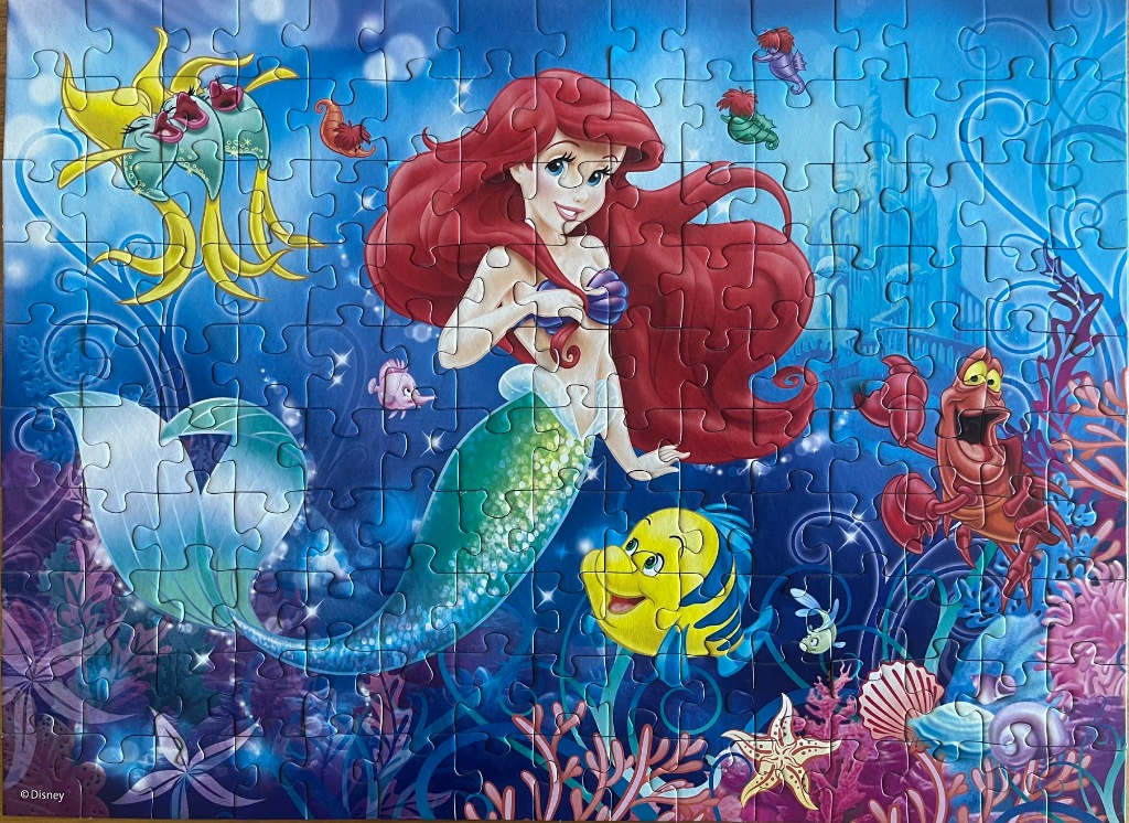 A vibrant underwater illustration featuring Ariel, Sebastian, and Flounder from The Little Mermaid.