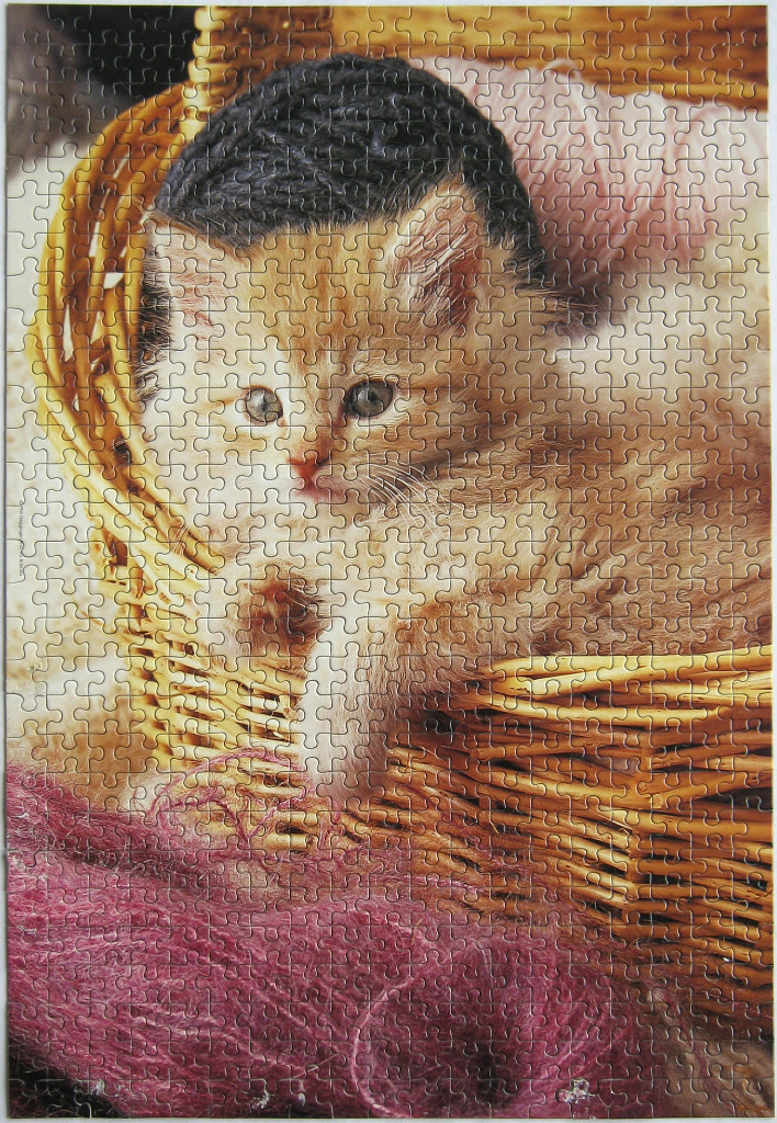 A fluffy ginger kitten sitting in a woven basket surrounded by yarn.