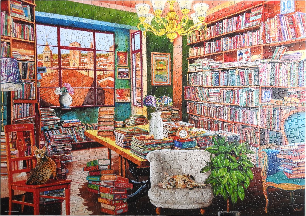 A cozy study filled with bookshelves, a large table with stacks of books, and two cats.