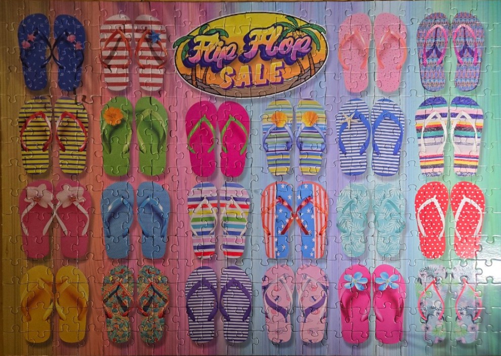 A collection of colorful pairs of flip-flops arranged in a grid against a rainbow-striped background.