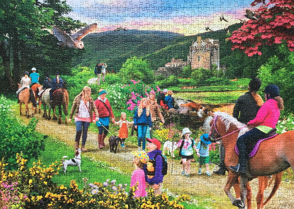 People horseback riding and walking their dogs near a Scottish castle at sunset