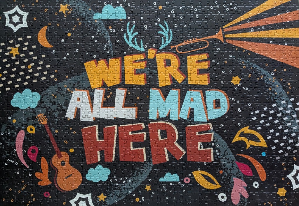 Typography art reading WE'RE ALL MAD HERE on a dark background with celestial and musical motifs.