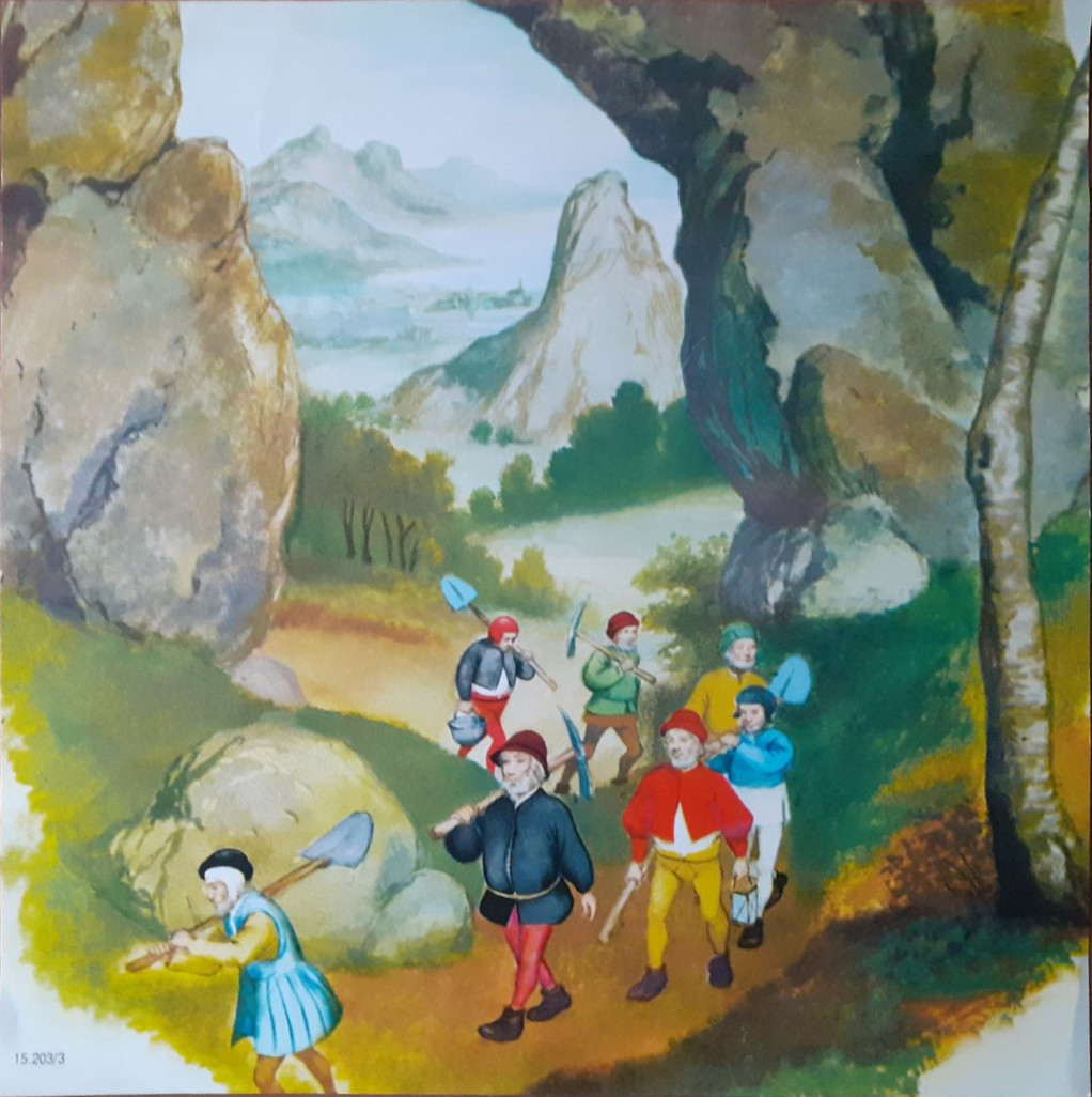 A group of seven small men with mining tools walking along a path between two large rock formations.