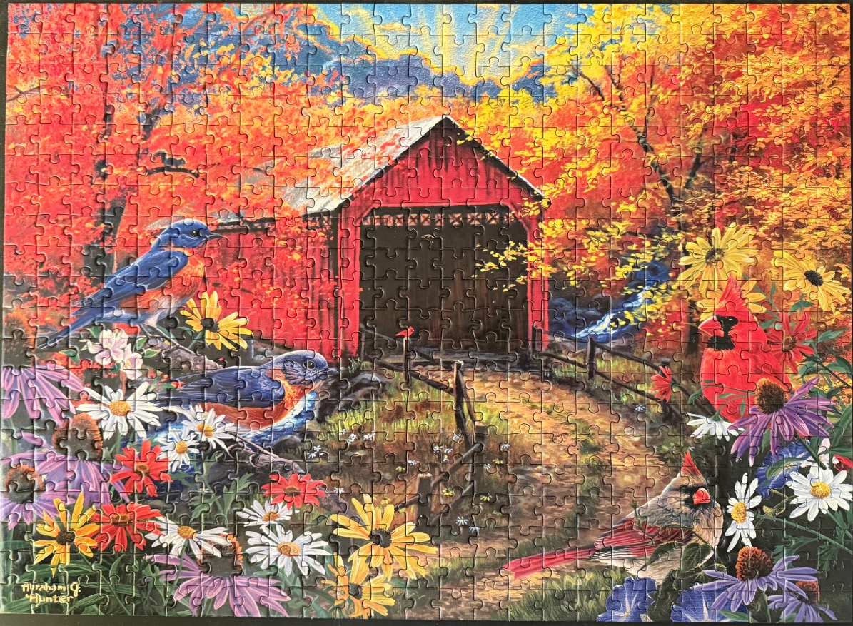 A vibrant autumn scene featuring a red covered bridge, bluebirds, cardinals, and colorful wildflowers.