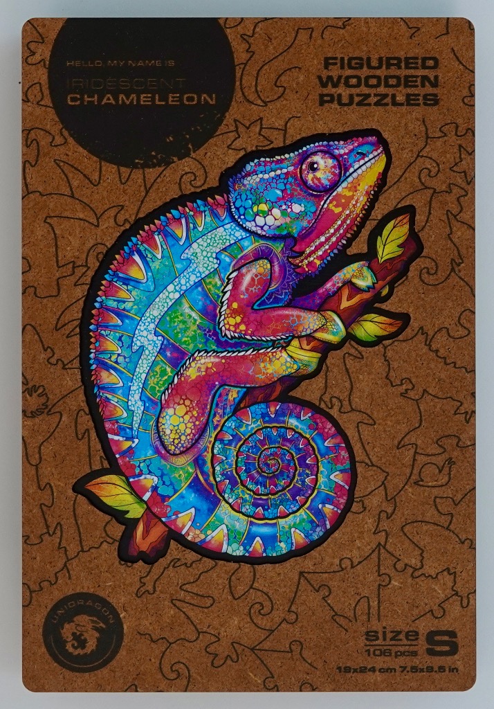 An illustration of an iridescent chameleon with vibrant patterns resting on a branch against a cork background.