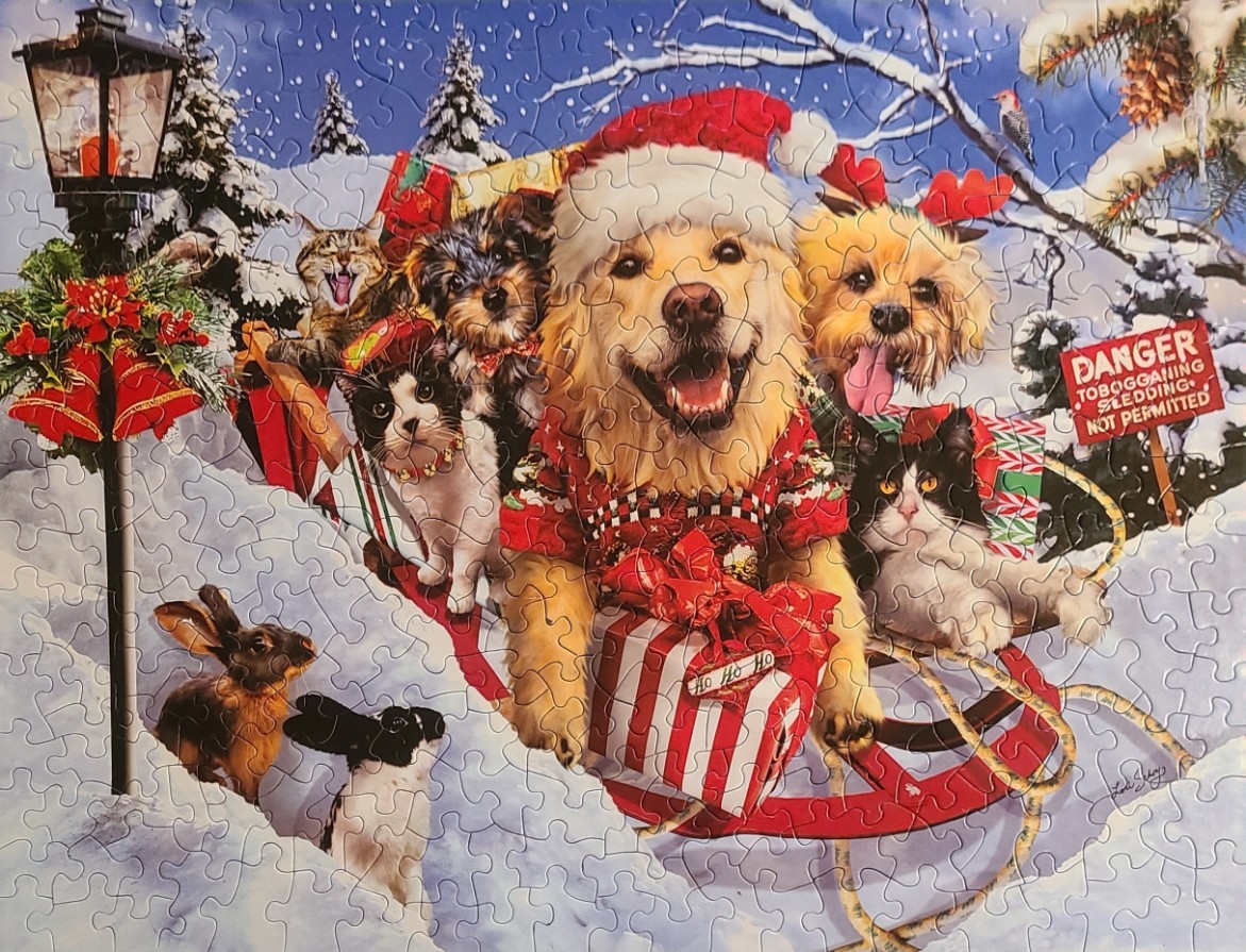 A group of dogs and cats wearing Christmas accessories on a red wooden sled in the snow.