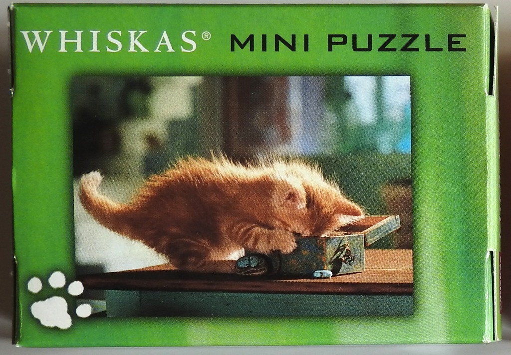 An orange kitten playing with a small wooden box on a table surface.