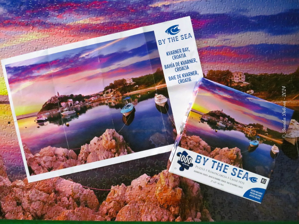 A scenic sunset view of Kvarner Bay, Croatia, featuring a calm harbor, rocky foreground, and a vibrant purple sky.