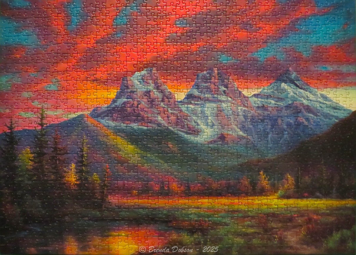 Vibrant mountain landscape at sunset with snow-capped peaks and a reflecting foreground pool.
