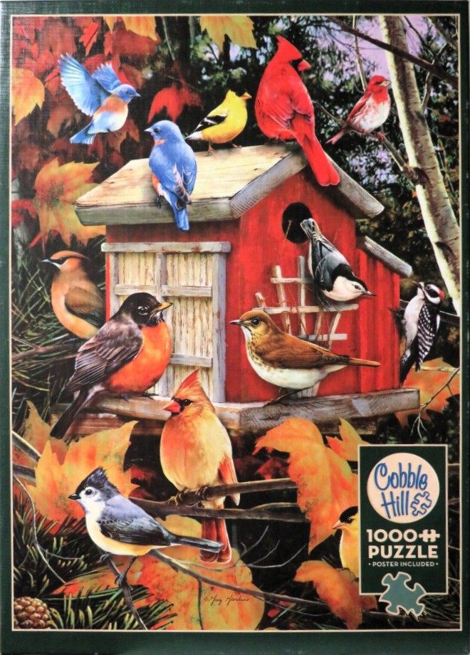 A variety of colorful birds perched on and around a red wooden birdhouse surrounded by autumn leaves.