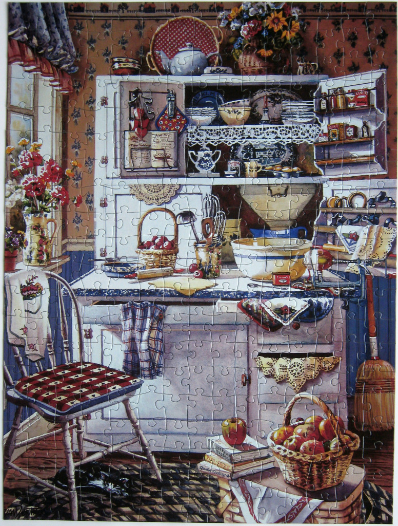 A cozy, vintage-style country kitchen interior with a wooden hutch, a basket of apples, and a black cat under a chair.