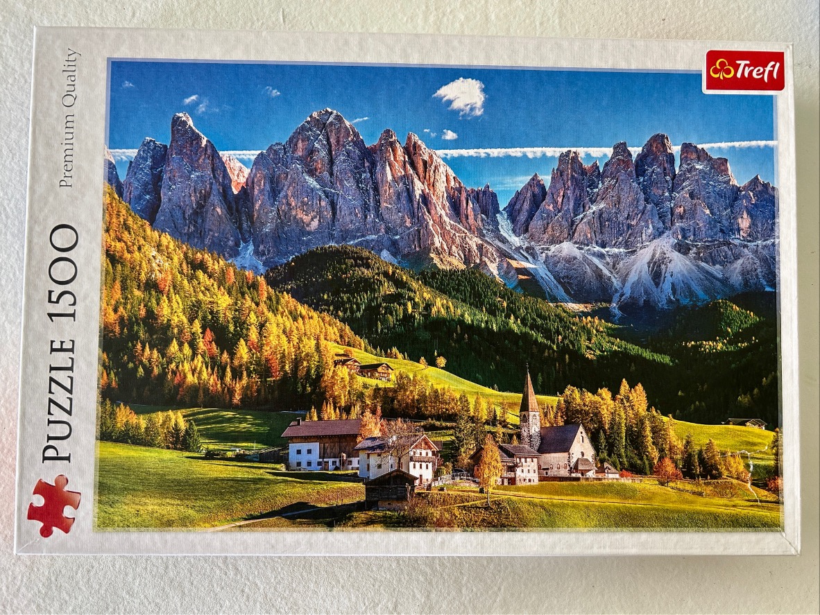 A scenic photograph of the Dolomite mountains in Italy during autumn, featuring a small village and church.