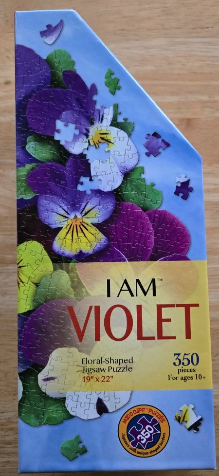 A collection of pansy flowers in shades of purple, yellow, and white against a light blue sky.