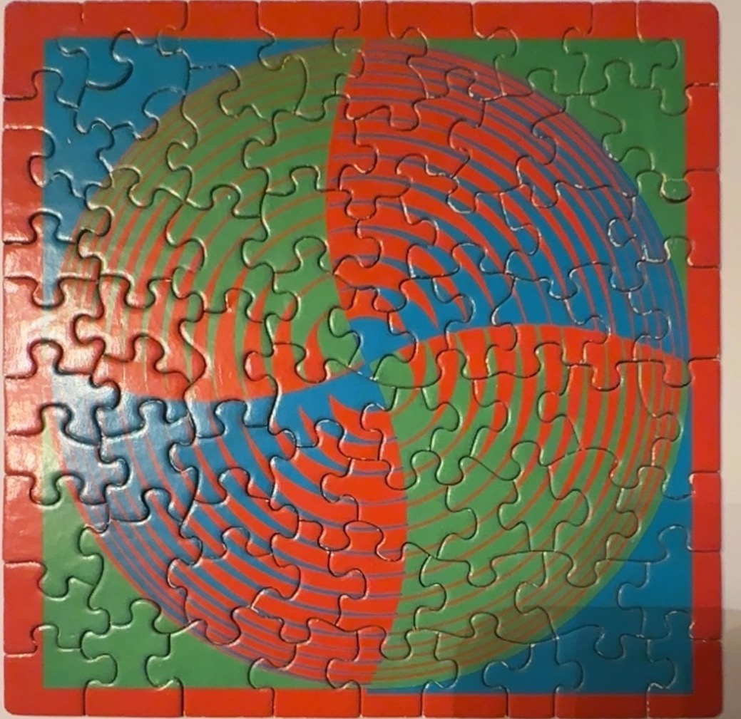 An abstract op-art design featuring a swirling pinwheel pattern in red, green, and blue.